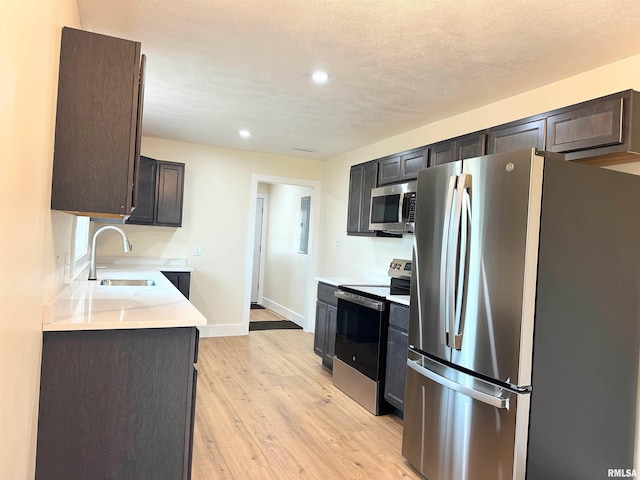 kitchen with sink, stainless steel appliances, dark brown cabinets, and light hardwood / wood-style flooring