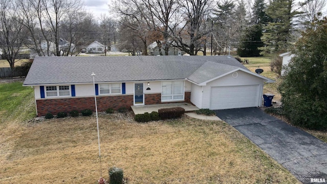 ranch-style house featuring a front yard, brick siding, driveway, and an attached garage