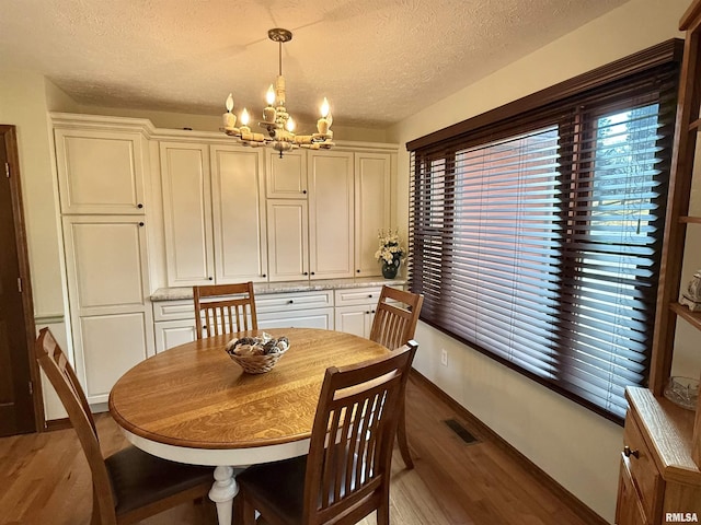 dining room featuring a chandelier, a textured ceiling, and dark wood-type flooring