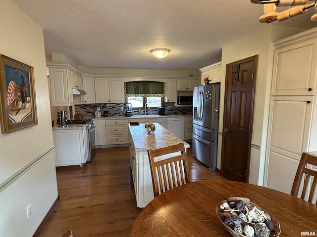 kitchen featuring a center island, sink, tasteful backsplash, white cabinetry, and stainless steel appliances