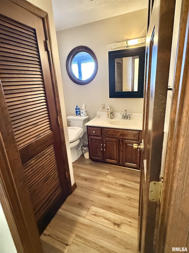 bathroom featuring hardwood / wood-style flooring, vanity, toilet, and a textured ceiling