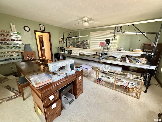 office area with a workshop area, ceiling fan, light carpet, and a textured ceiling