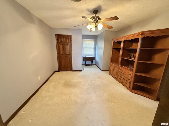 spare room with a textured ceiling, light colored carpet, and ceiling fan