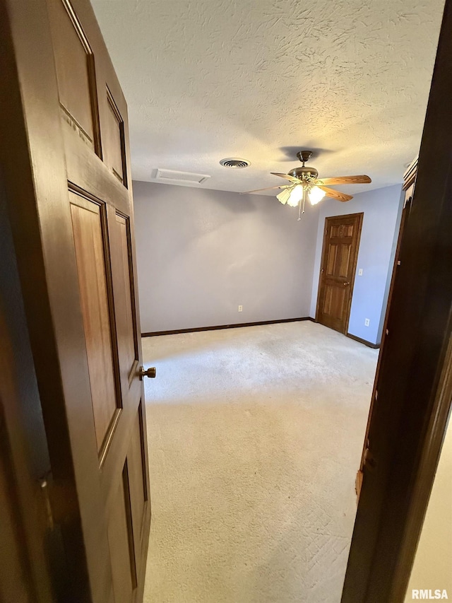 carpeted spare room featuring a textured ceiling and ceiling fan