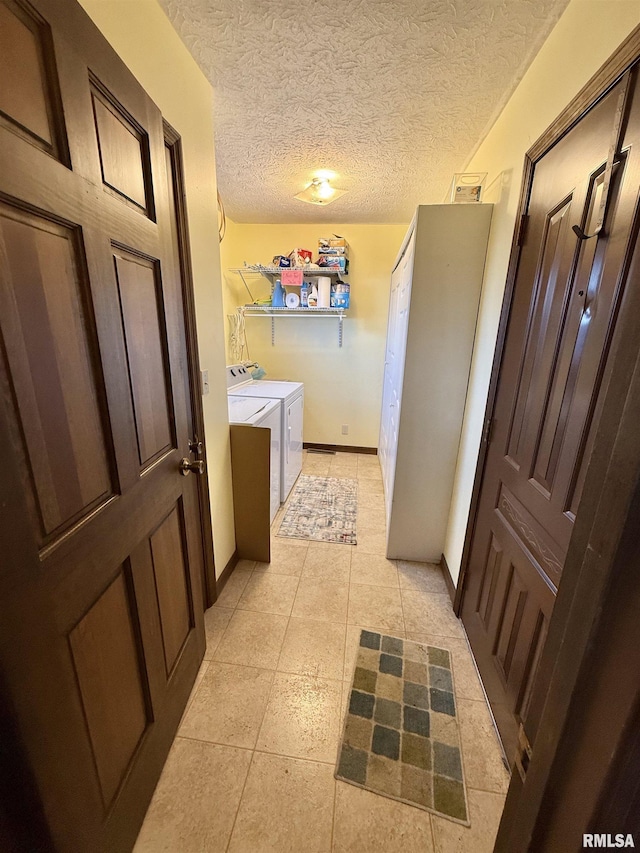 bathroom with tile patterned flooring, a textured ceiling, and washing machine and clothes dryer