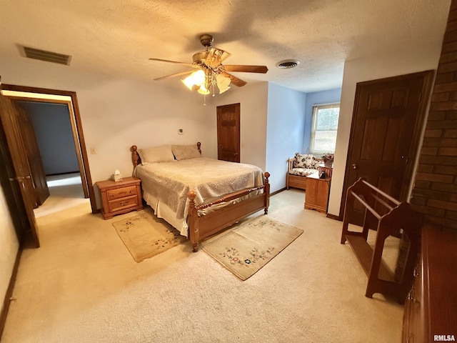 bedroom featuring a textured ceiling, light colored carpet, and ceiling fan