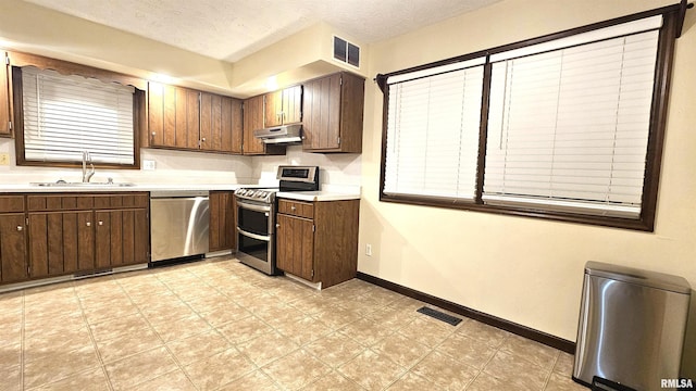 kitchen featuring a textured ceiling, dark brown cabinets, sink, and appliances with stainless steel finishes