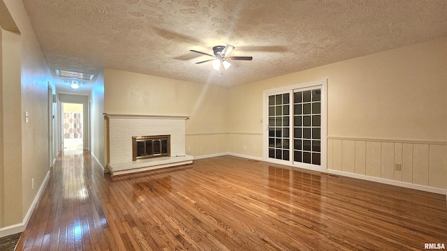 unfurnished living room featuring a fireplace, wood-type flooring, a textured ceiling, and ceiling fan