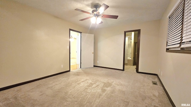 unfurnished bedroom featuring ensuite bathroom, ceiling fan, light colored carpet, and a textured ceiling