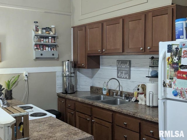 kitchen featuring white refrigerator, dark brown cabinetry, and sink