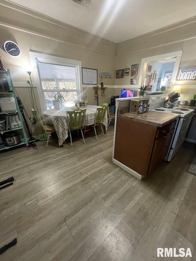 kitchen featuring white range with electric cooktop, kitchen peninsula, and hardwood / wood-style flooring