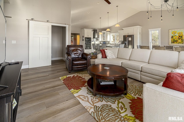 living room featuring a barn door, hardwood / wood-style flooring, and high vaulted ceiling