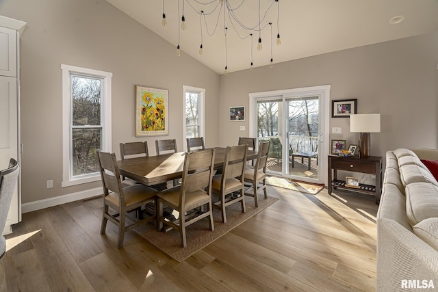 dining area with hardwood / wood-style floors, a towering ceiling, and an inviting chandelier