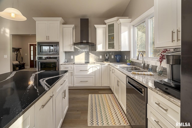 kitchen featuring wall chimney exhaust hood, sink, black appliances, decorative light fixtures, and white cabinetry