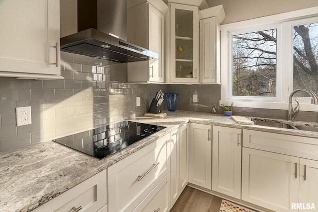 kitchen with white cabinetry, sink, wall chimney range hood, decorative backsplash, and black electric stovetop