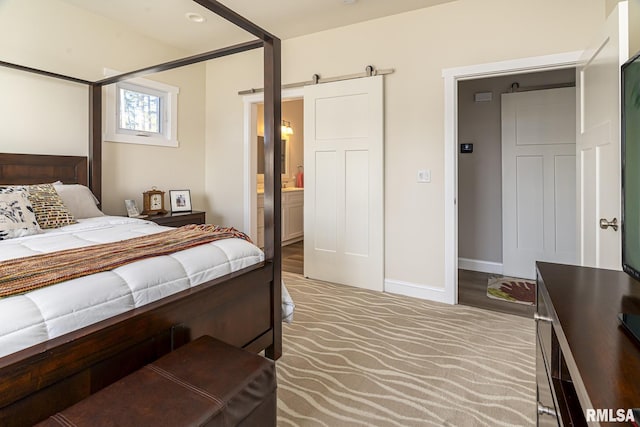 carpeted bedroom with a barn door and ensuite bathroom