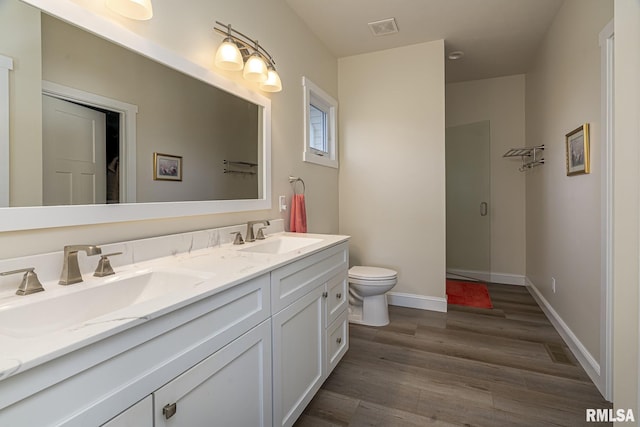 bathroom with hardwood / wood-style floors, vanity, toilet, and walk in shower