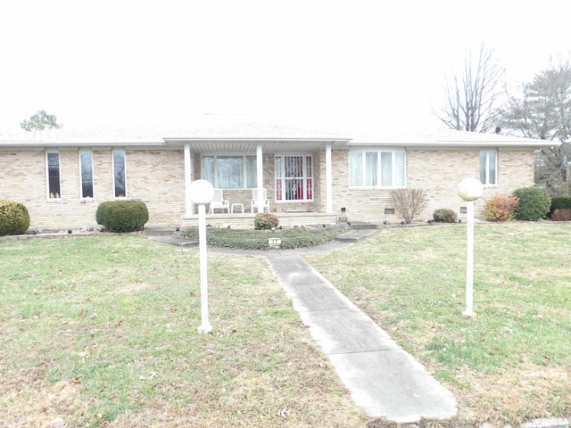 ranch-style home featuring a front lawn and covered porch