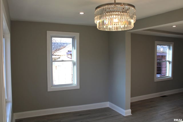 spare room featuring dark hardwood / wood-style flooring and an inviting chandelier