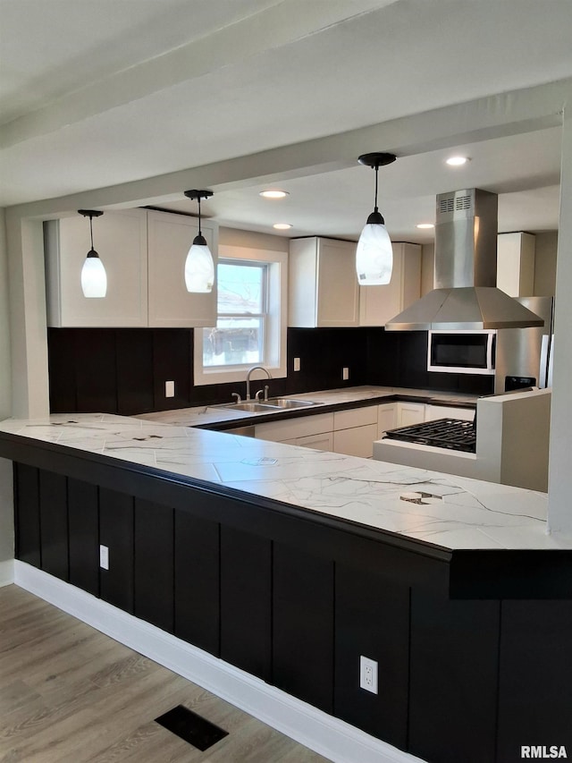 309 W 11th St, Metropolis, IL 62960 - kitchen with white cabinetry, light stone countertops, a sink, wall chimney range hood, and a peninsula
