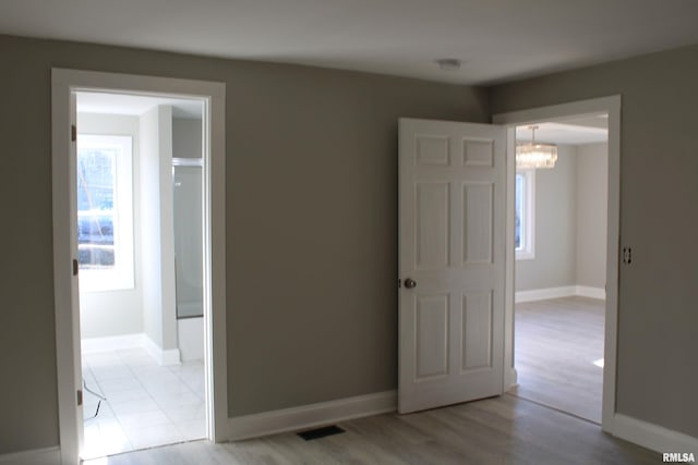 unfurnished bedroom with light wood-type flooring and an inviting chandelier