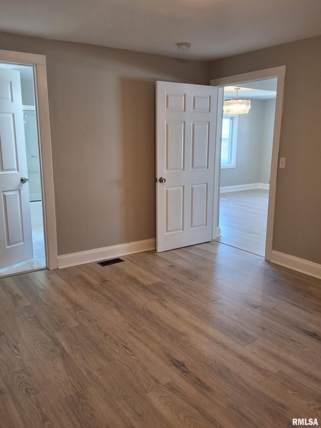 309 W 11th St, Metropolis, IL 62960 - empty room with baseboards, a notable chandelier, visible vents, and wood finished floors