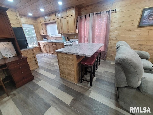 kitchen with a breakfast bar, white range, a kitchen island, and wood walls