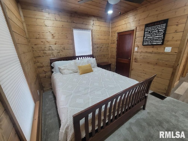 carpeted bedroom featuring wood walls and ceiling fan