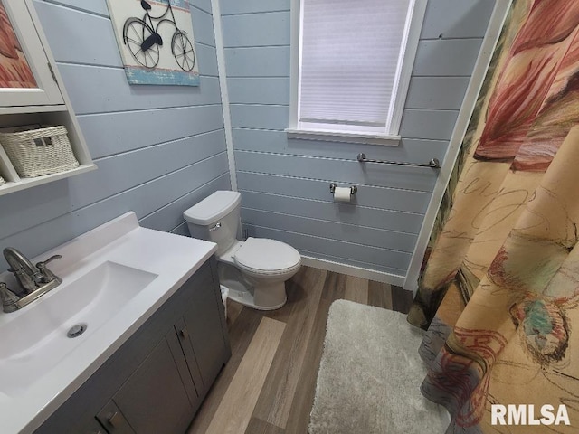 bathroom with hardwood / wood-style flooring, vanity, wood walls, and toilet