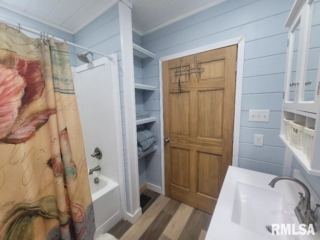 bathroom featuring shower / bath combo with shower curtain, wooden walls, sink, and wood-type flooring