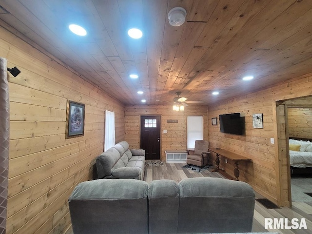 living room featuring light wood-type flooring, ceiling fan, wooden walls, and wood ceiling