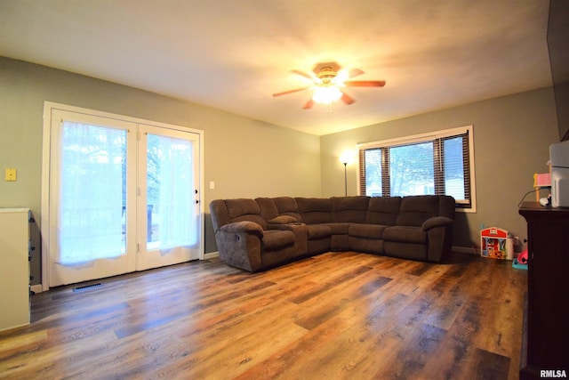 living room featuring ceiling fan and dark wood-type flooring