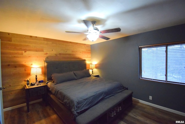 bedroom with ceiling fan, dark hardwood / wood-style floors, and wood walls