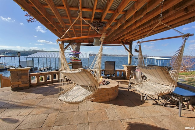 view of patio / terrace with a boat dock, a water view, and an outdoor fire pit