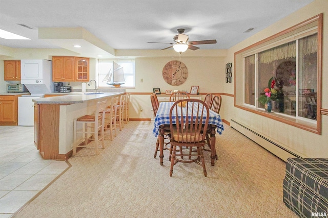 carpeted dining room with baseboard heating, ceiling fan, and sink