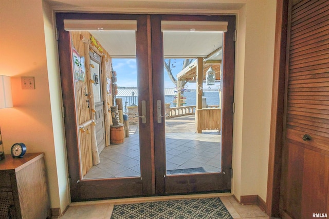 doorway with a water view, light tile patterned floors, and french doors