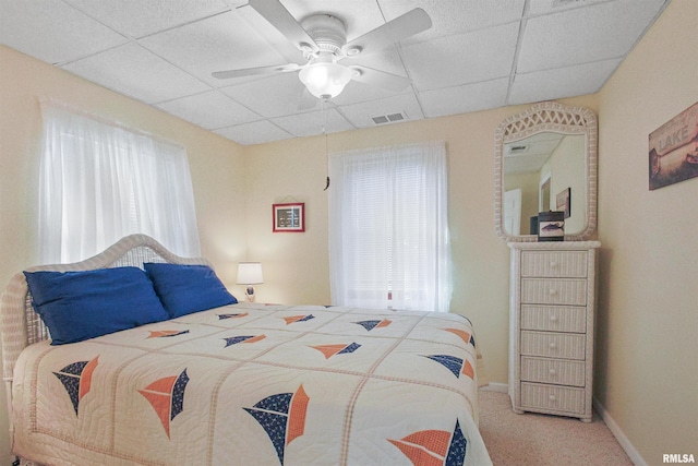 carpeted bedroom with ceiling fan and a drop ceiling