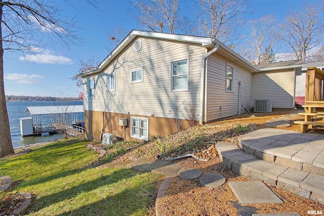 rear view of house featuring a water view, central AC unit, and a lawn