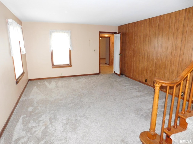 carpeted spare room featuring wood walls