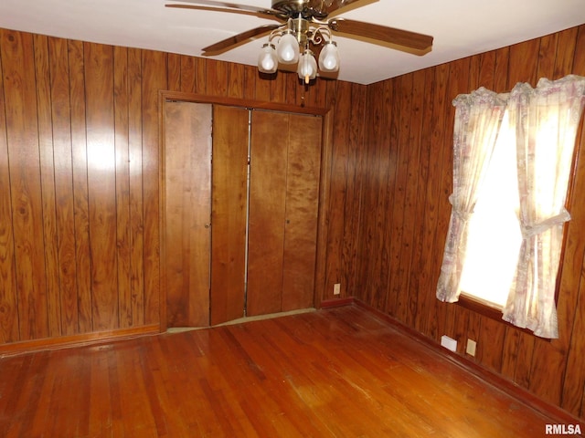 spare room with wooden walls, hardwood / wood-style floors, and a healthy amount of sunlight