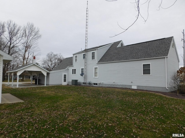 rear view of property featuring a carport, a yard, and central AC