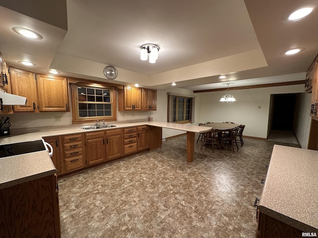 kitchen featuring sink, ventilation hood, a chandelier, pendant lighting, and range