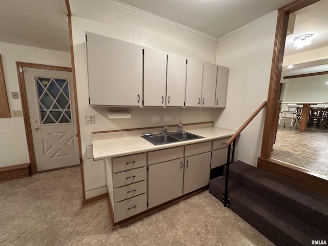 kitchen with white cabinetry, sink, and ornamental molding