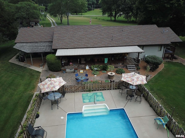 view of pool with a wooden deck, exterior bar, central AC unit, a patio area, and a yard