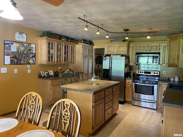 kitchen with appliances with stainless steel finishes, a center island, track lighting, and sink