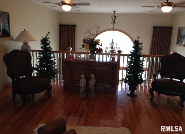 living area featuring ceiling fan with notable chandelier and dark wood-type flooring