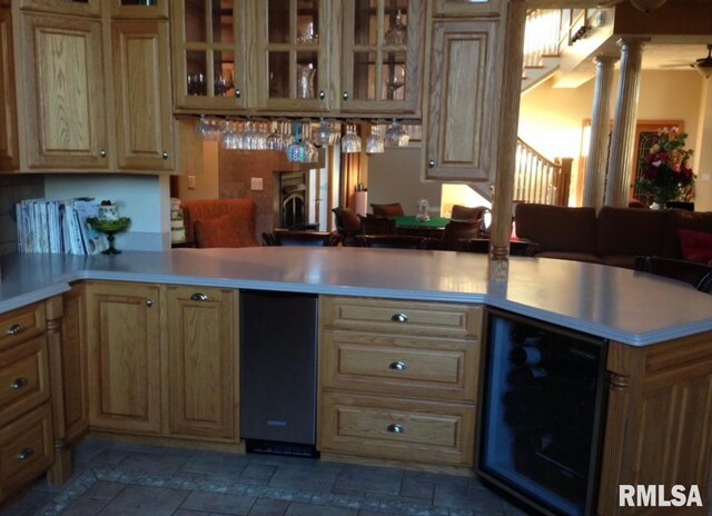 kitchen featuring ornate columns, kitchen peninsula, and wine cooler