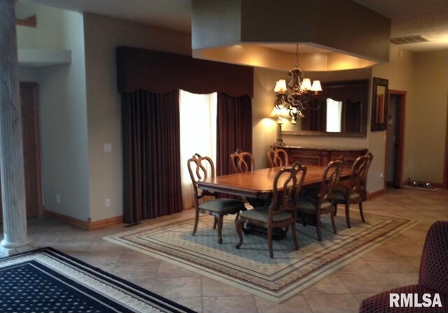 tiled dining area featuring an inviting chandelier and ornate columns