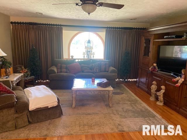 living room with a textured ceiling, hardwood / wood-style flooring, and ceiling fan