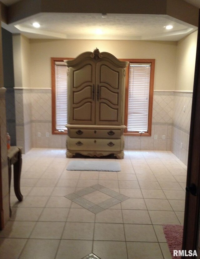 interior space featuring light tile patterned floors and tile walls